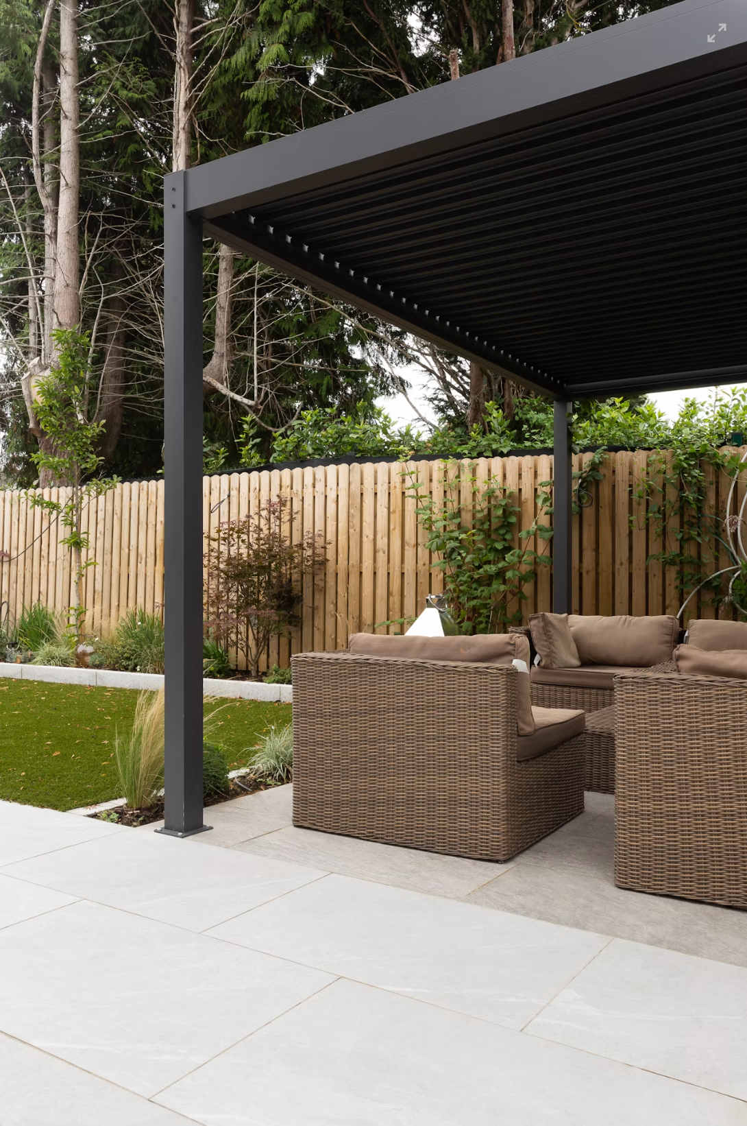 Charcoal aluminum pergola frame and louvered roof over a garden patio